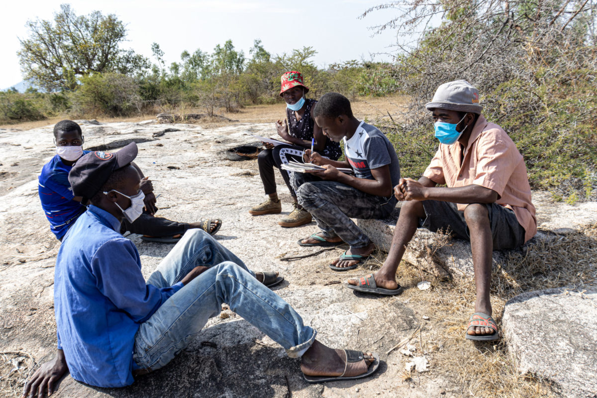 June 01, 2021: Desmond, far back with a red hat, sits with his peers as they conduct a discussion using the community visioning tools. Upon completion, Desmond and his peers went on to facilitate discussions for other sub-groups in VIDCO 3. © Charmaine Chitate/ CARE