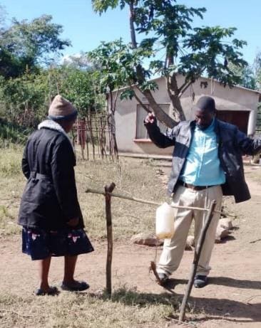 July 4, 2022: Self-motivated Mutupo Munyetu demonstrating on the proper use of handwashing facility to his visitor at his household in Chinoona Village © Mercy Jamba/ CARE 2022